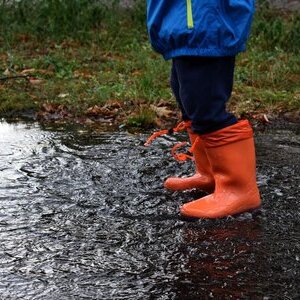 Kind mit Gummistiefeln in einem Bach