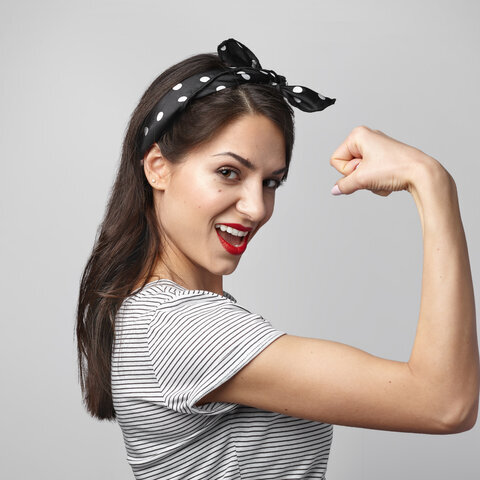 Portrait of strong independent female wearing headscarf and stylish sailor shirt showing her bicep at camera, having excited expression. People, strength, power, sports, energy and fitness concept